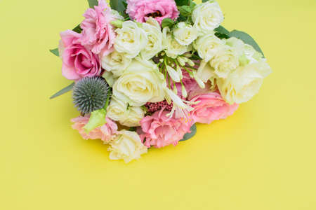 Colorful beautiful bouquet of different fresh flowers on the yellow background. Floral arrangement. Top view.の写真素材