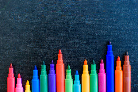 Open multicolored markers closeup on black board background. Place for text.の写真素材