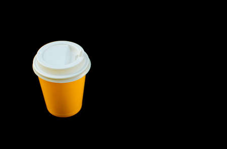Yellow paper cup with white lid isolated on black background. Place for text.