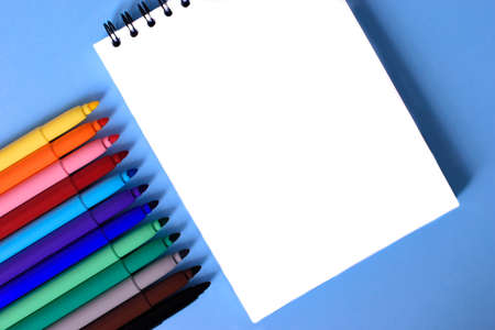 Open notepad and open multicolored markers on the blue background. Place for text. Concept back to school.の写真素材