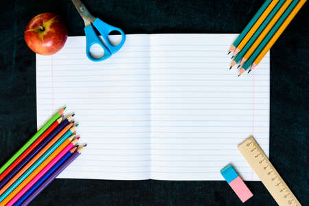 Office and school supplies on black board background with copy space. Back to school concept. Flat...