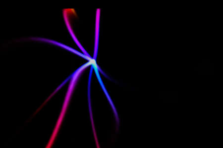 Glowing neon lines on a black background. Multicolor star shaped defocused lines. Blurred abstract...
