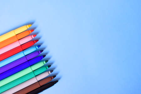 Open multicolored markers closeup on a blue background. Concept back to school. Place for text.