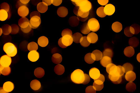 Blurred abstract gold glitter texture, defocused christmas lights on black background. Holiday...
