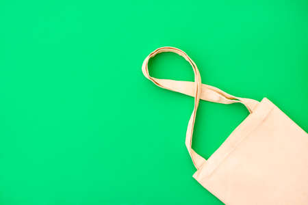 Canvas cotton white bag on the bright green background. Eco Friendly reusable bag for groceries and shopping. Eco and zero waste concept. Close up.の写真素材