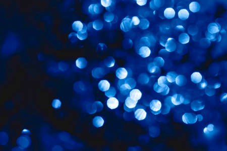 Abstract bright sparkling background, defocused christmas lights. Blurred background for holidays and parties in blue colors. Color of the year 2020.の写真素材