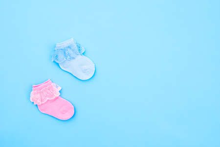 Two pair blue and pink cute baby socks on blue background. Baby accessories. Flat lay.