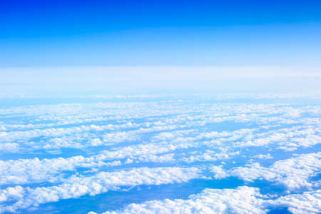 View on the blue sky with clouds from airplane window.