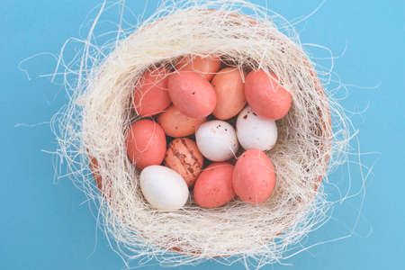 Decorative bird nest with colorful easter eggs on blue pastel background. Easter concept. Flat lay.の写真素材
