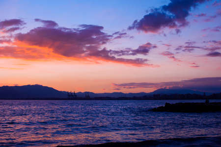 Nature in twilight period on the sea, sunset over the mountain. Beautiful clouds painted in orange color. Nature background.の写真素材