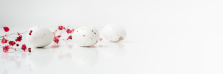 Easter minimal composition with eggs and flowers on the white background. Easter concept. Copy space, flat lay. Banner.の写真素材