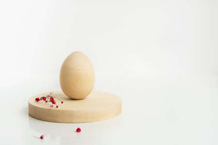 Easter creative minimal composition with wooden egg and flowers on the wooden cylinder shapes....