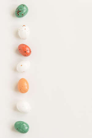 Easter minimal composition with multicolored eggs on the white background. Easter concept. Copy space, flat lay. Vertical photo.の写真素材