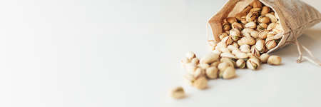 Pile of pistachios on the light background. Pistachio is a healthy vegetarian protein nutritious food. Vegetarian food concept. Banner.の写真素材