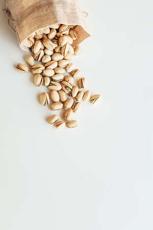 Pile of pistachios on the light background. Pistachio is a healthy vegetarian protein nutritious food. Vegetarian food concept. Vertical photo.の写真素材