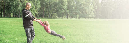 Father playing with his cute little daughter on the field. Concept of friendly family. Great family vacation. Banner.の写真素材