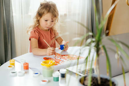 Young cute girl spending a time drawing using online lessons on laptop. Distance learning, online education.の写真素材