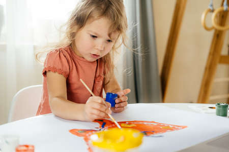 Young girl spending a time drawing using online lessons on laptop at home. Distance learning, online education.の写真素材