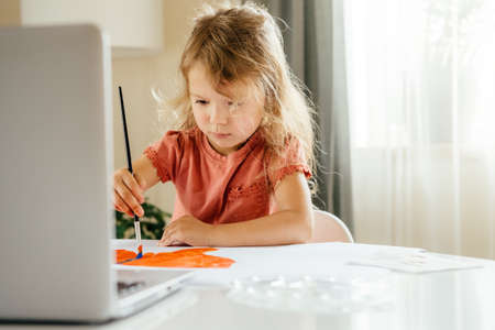 The girl spending a time drawing the picture using laptop at home. Distance learning, online education.の写真素材