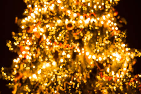 Defocused background of Christmas tree with garlands. Glowing illumination bokeh. Atmospheric...