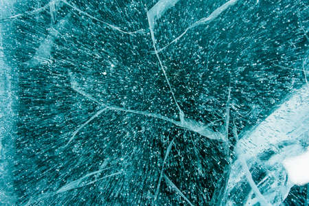 Texture of beautiful blue ice with cracks and air bubbles in the frozen lake. Winter nature...
