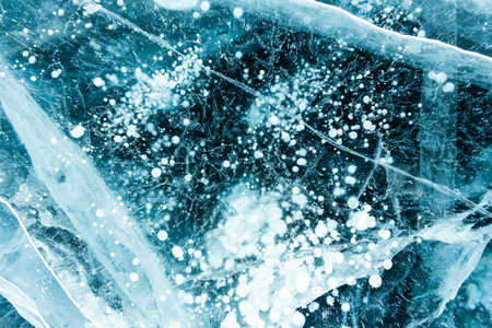 Texture of beautiful blue ice with cracks and air bubbles in the frozen lake. Winter nature...