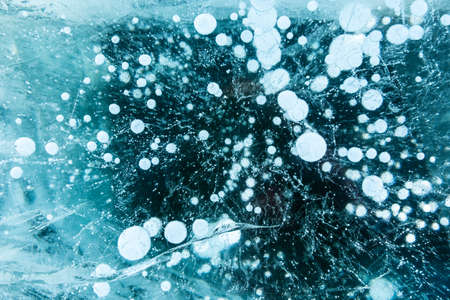 Texture of beautiful blue ice with cracks and air bubbles in the frozen lake. Winter nature...