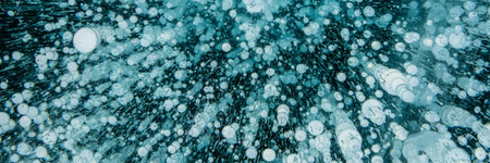 Texture of beautiful blue ice with cracks and air bubbles in the frozen lake. Winter nature background. Banner.の写真素材