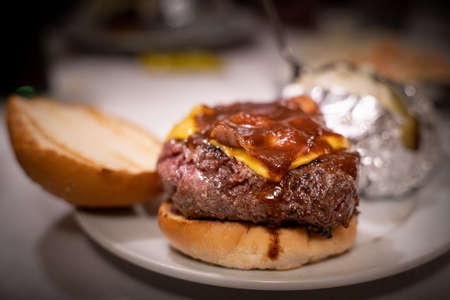 A juicy and appetizing burger with crispy bacon and melted cheese and dripping sauceの写真素材