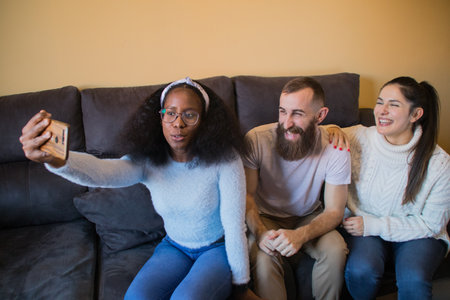 Multiethnic group having a selfie at home sitting on the sofaの写真素材