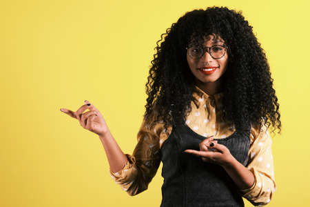 afro american woman with yellow background with copy space for product placementの写真素材