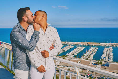 a gay couple on a sunny summer day with the sea behind themの写真素材