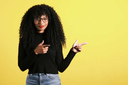 afro american woman with yellow background with copy space for product placementの写真素材