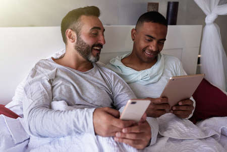 an interracial gay couple in bedの写真素材