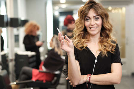 a young attractive woman at her beauty salon with clients behind herの写真素材