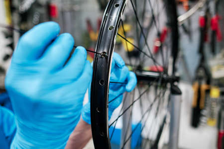 Man hands repairing spoke on bike wheelの写真素材