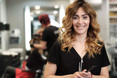 a young attractive woman at her beauty salon with clients behind herの写真素材
