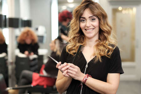 a young attractive woman at her beauty salon with clients behind herの写真素材