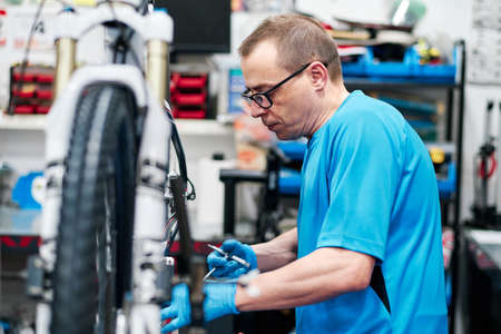 a man repairs a bike in his small business workshopの写真素材