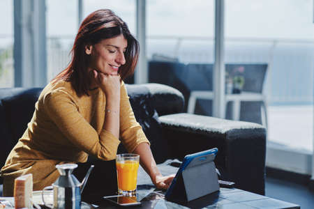 A young business woman working with a tablet and having a mediterranean breakfastの写真素材