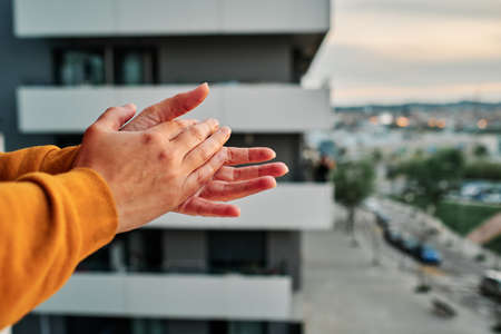 a woman claps her hands to congratulate healthcare system in Spain during coronavirus outbreak