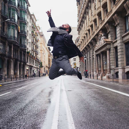 a young man jumps in Via Laietana, Barcelona, in a winter and rainy day