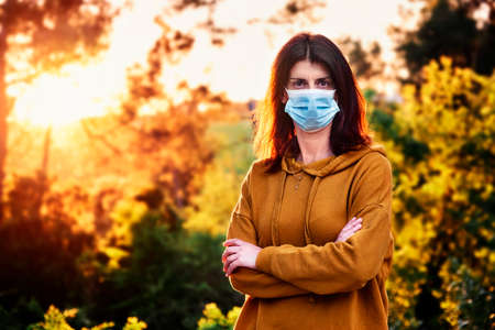 woman with face mask during coronavirus crisis in a natural environment - social distancing conceptの写真素材
