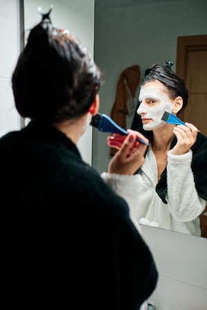 woman using facial mask with brush and towelsの写真素材