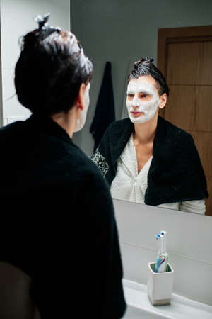 woman using facial mask with brush and towelsの写真素材