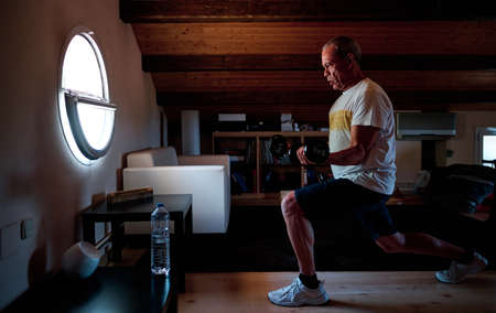 Man holding dumbbell and excersising at homeの写真素材