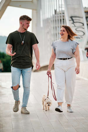 beautiful curvy model and handsome man taking a walk with their dog in an urban sceneの写真素材