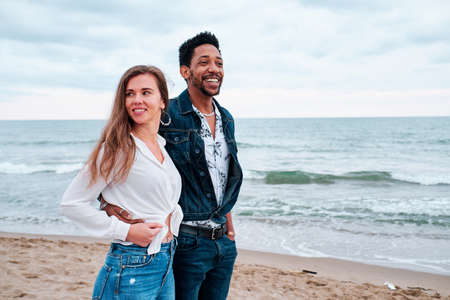 young interracial couple at the beach taking a walkの写真素材