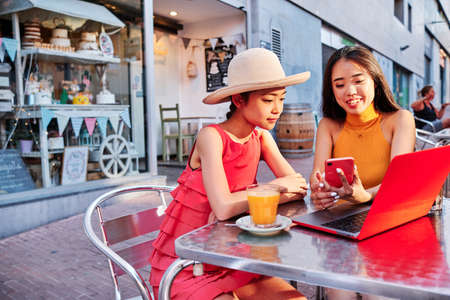 two asian women using a computer outdoorの写真素材