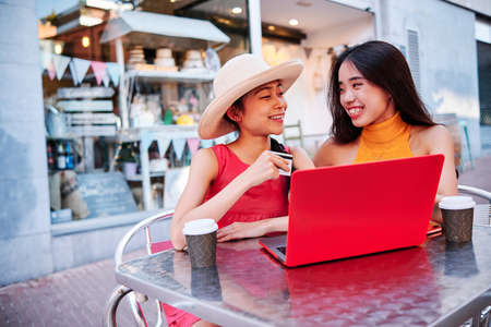 two asian girls using a credit card to pay or purchase using a notebookの写真素材